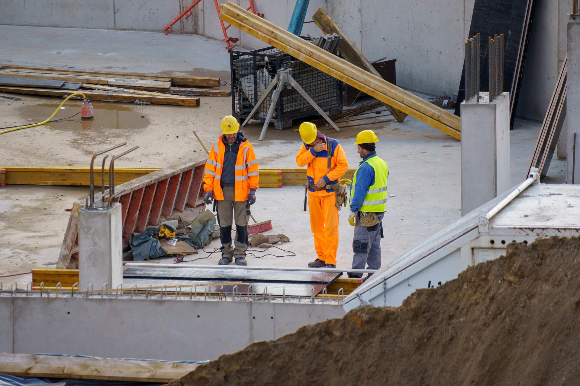 Construction workers in hard hats and safety vests collaborating on an active commercial job site