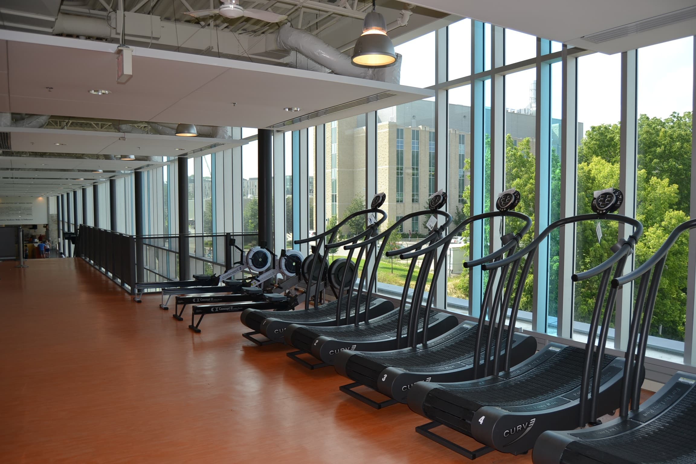 Modern fitness center with treadmills and rowing machines along floor-to-ceiling windows