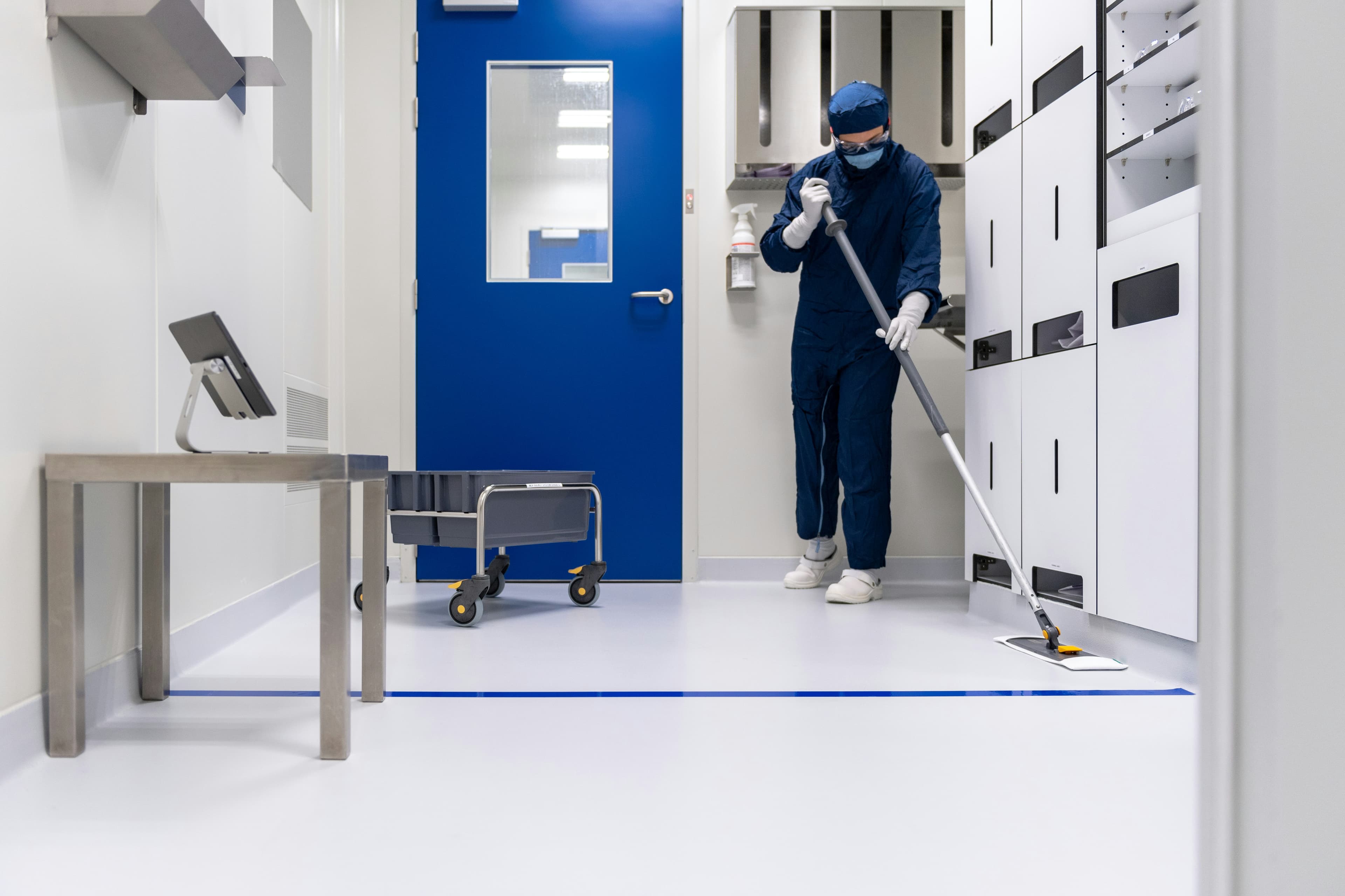 Professional cleaner sanitizing a medical facility floor in full protective gear