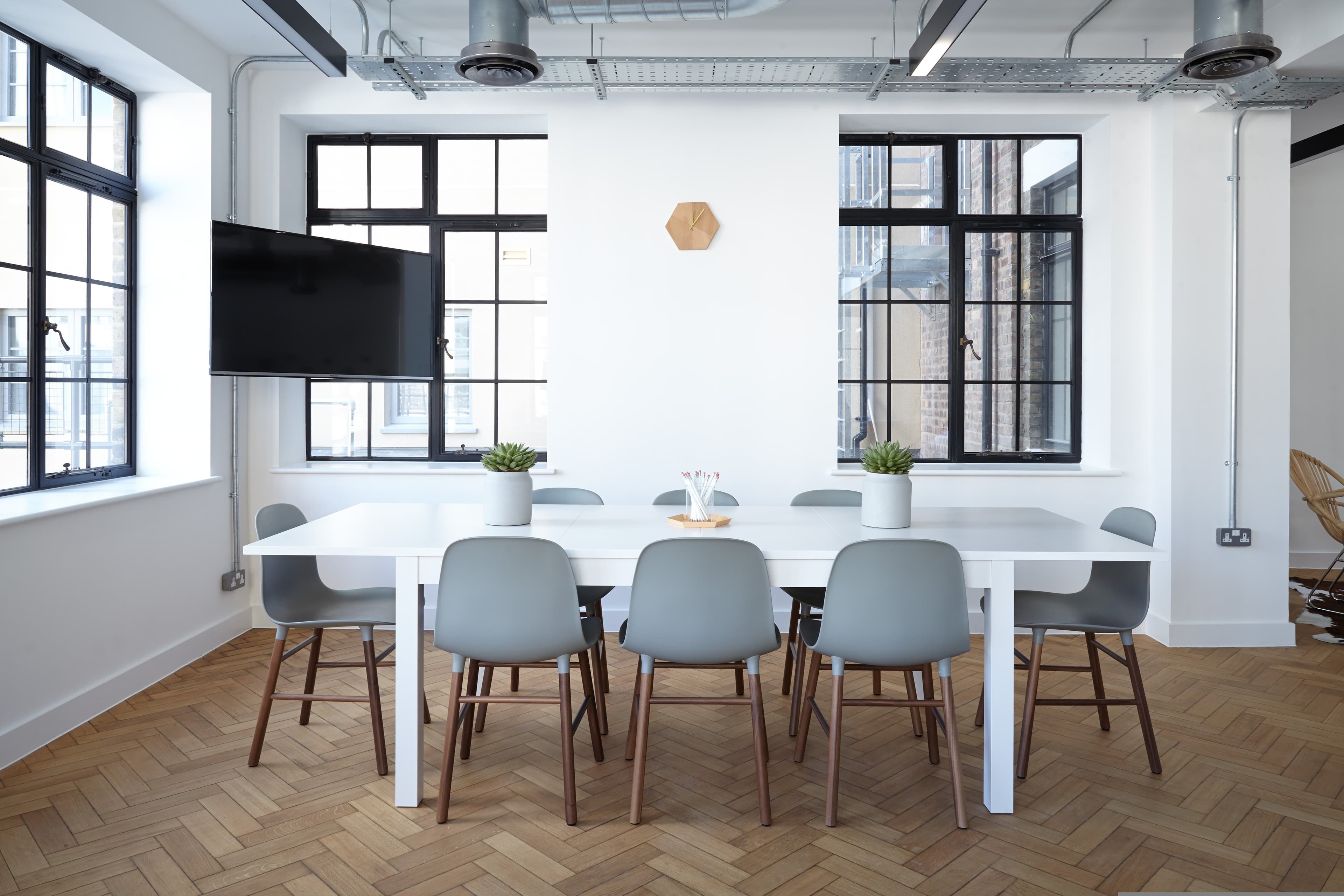 Clean modern office conference room with herringbone wood floors and natural light