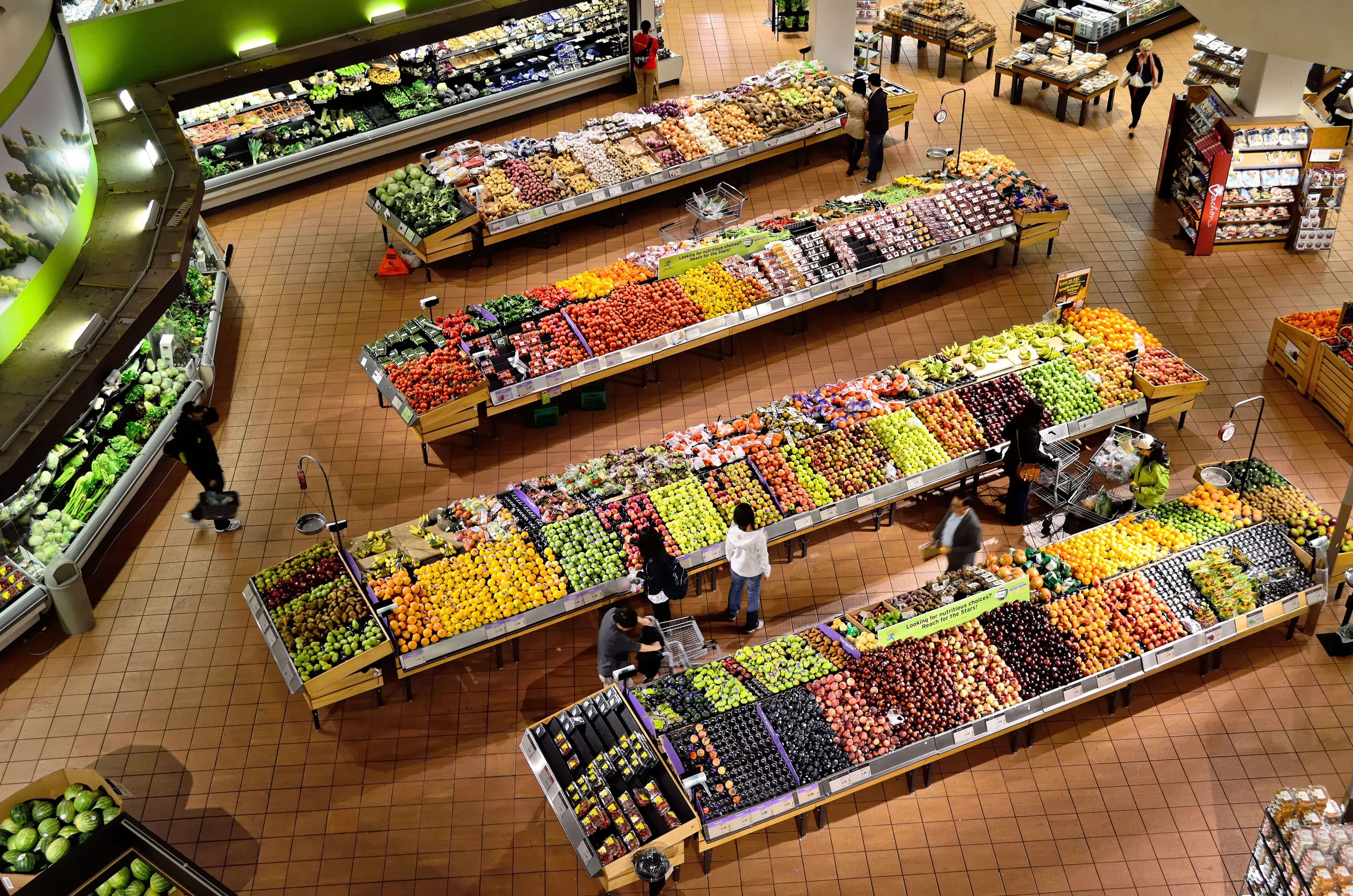 Aerial view of a large retail grocery store with colorful produce displays and shoppers