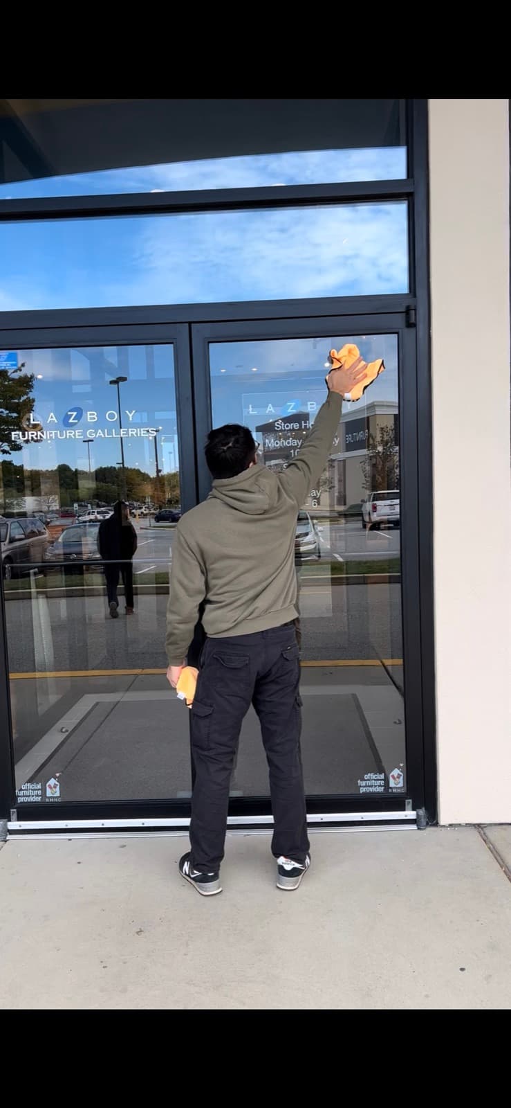 Crew member cleaning the entrance windows of a commercial retail storefront