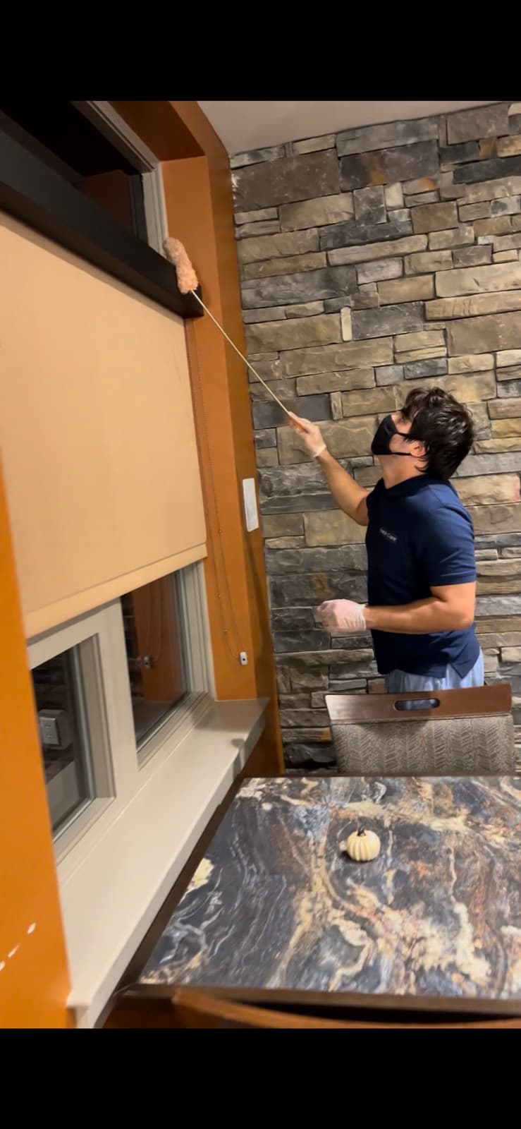 Space Care technician high-dusting blinds in a restaurant interior