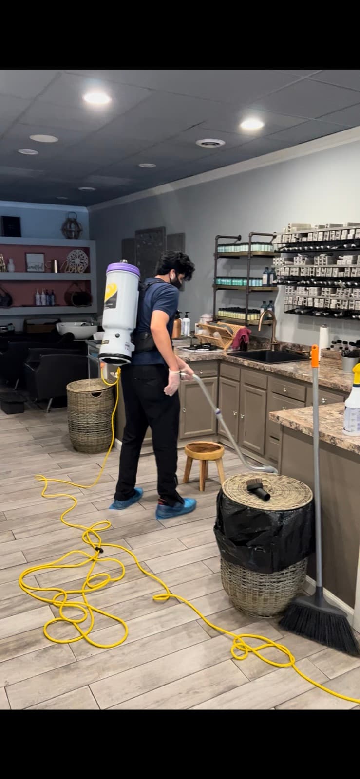 Space Care technician using a backpack vacuum on a salon floor