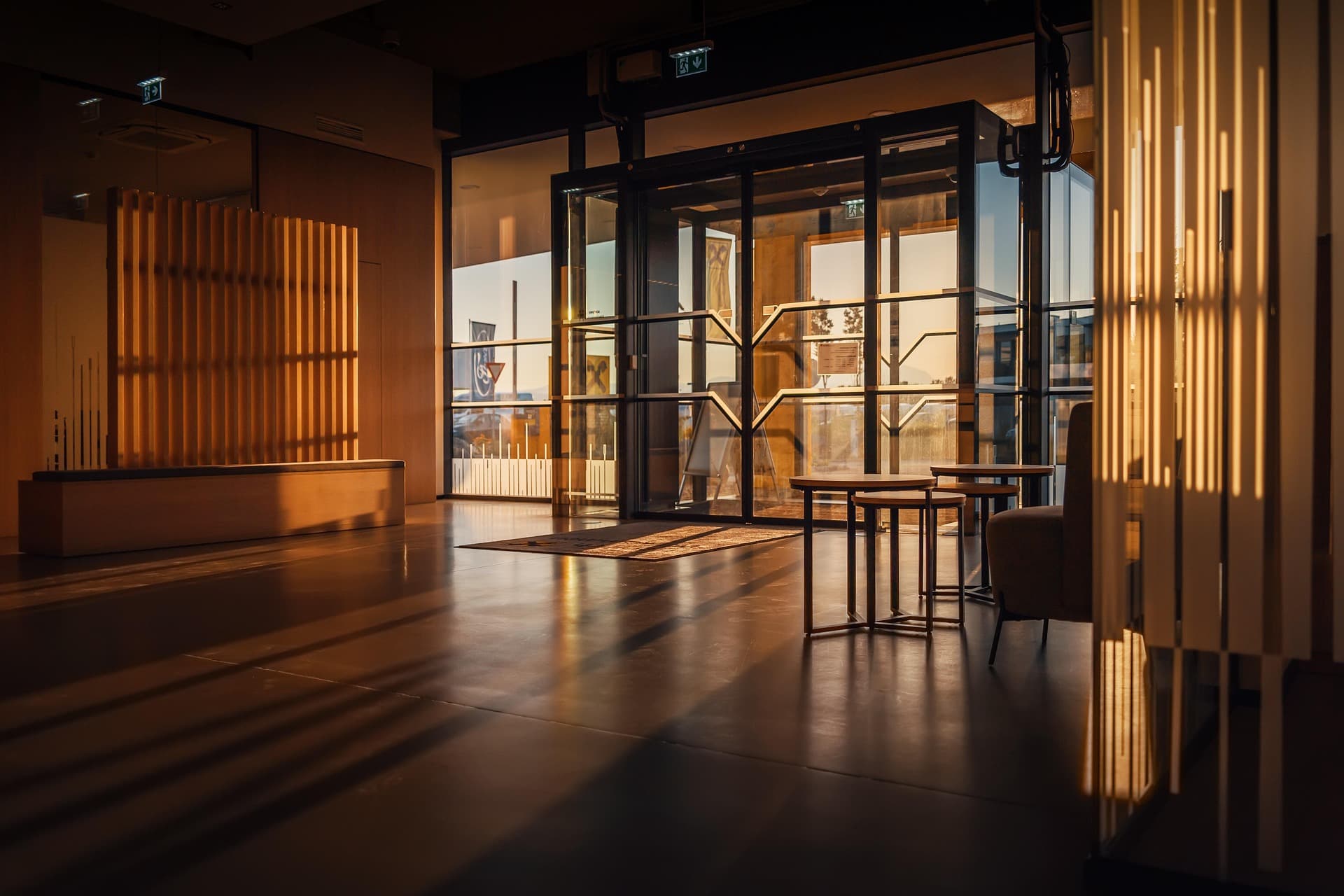 Modern commercial building lobby with warm golden light streaming through glass entrance doors