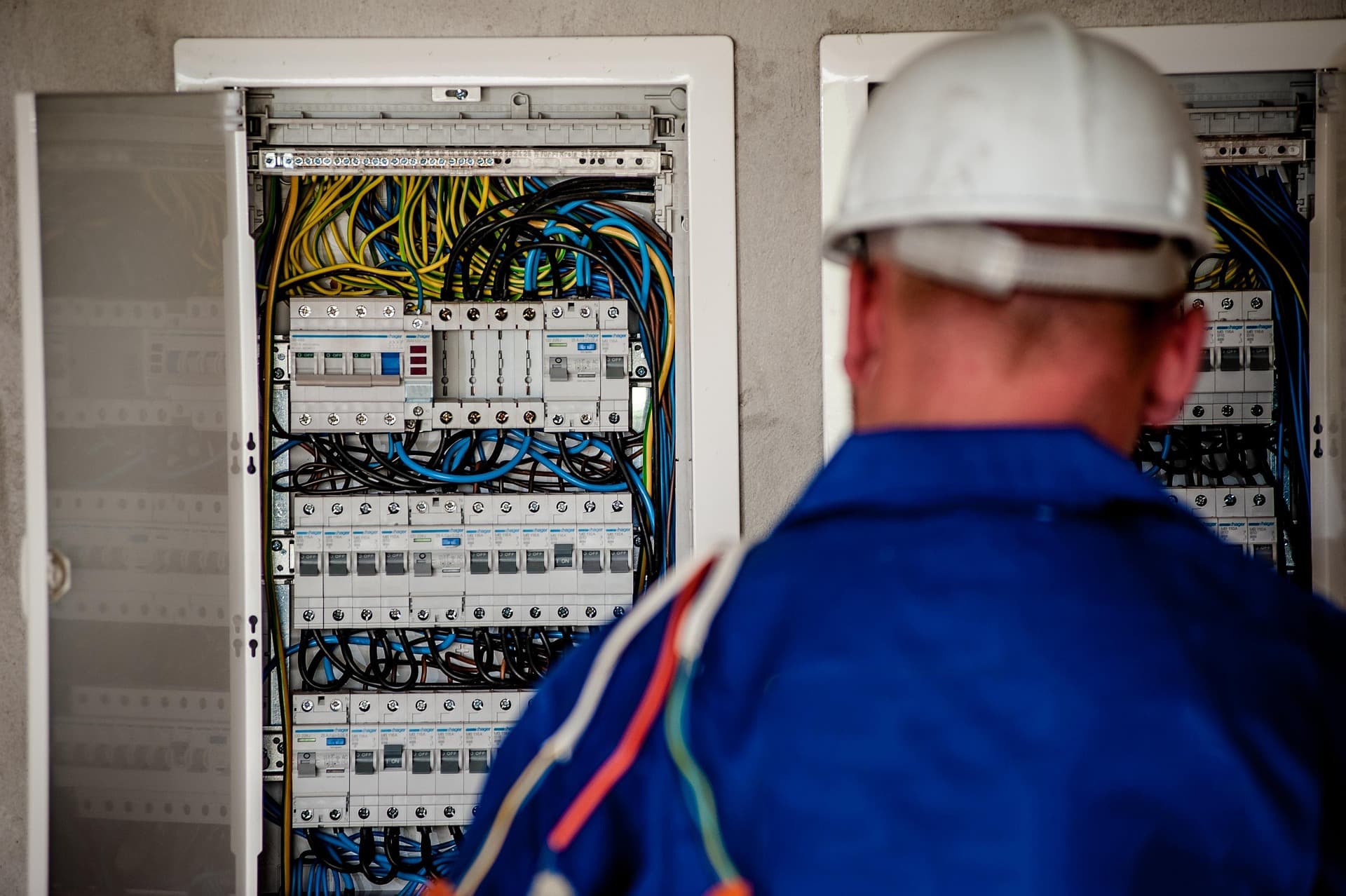 Licensed electrician inspecting a commercial electrical panel with circuit breakers and wiring