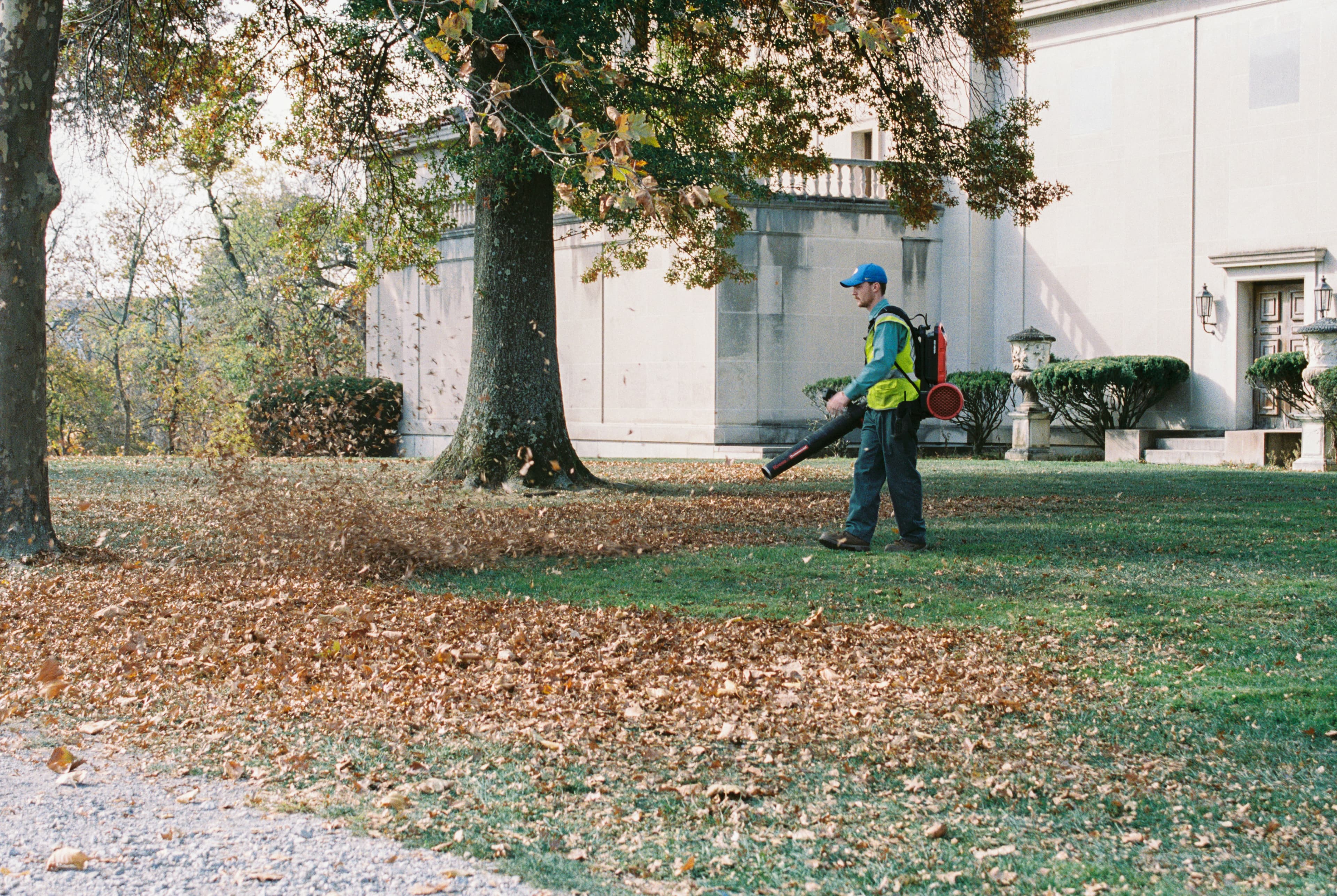 Grounds maintenance worker clearing leaves from a commercial property exterior