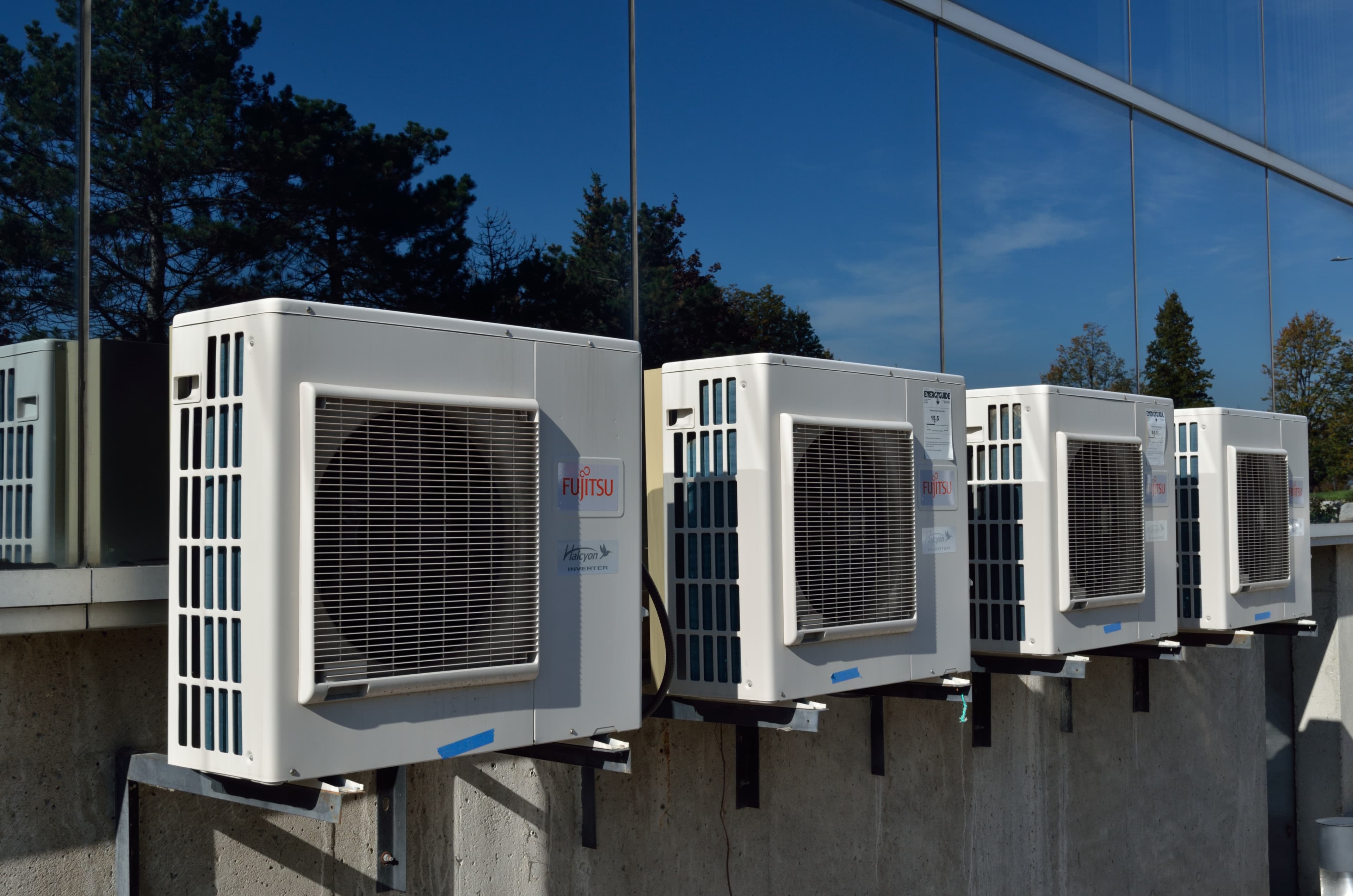 Row of commercial HVAC condenser units mounted on the exterior wall of a commercial building