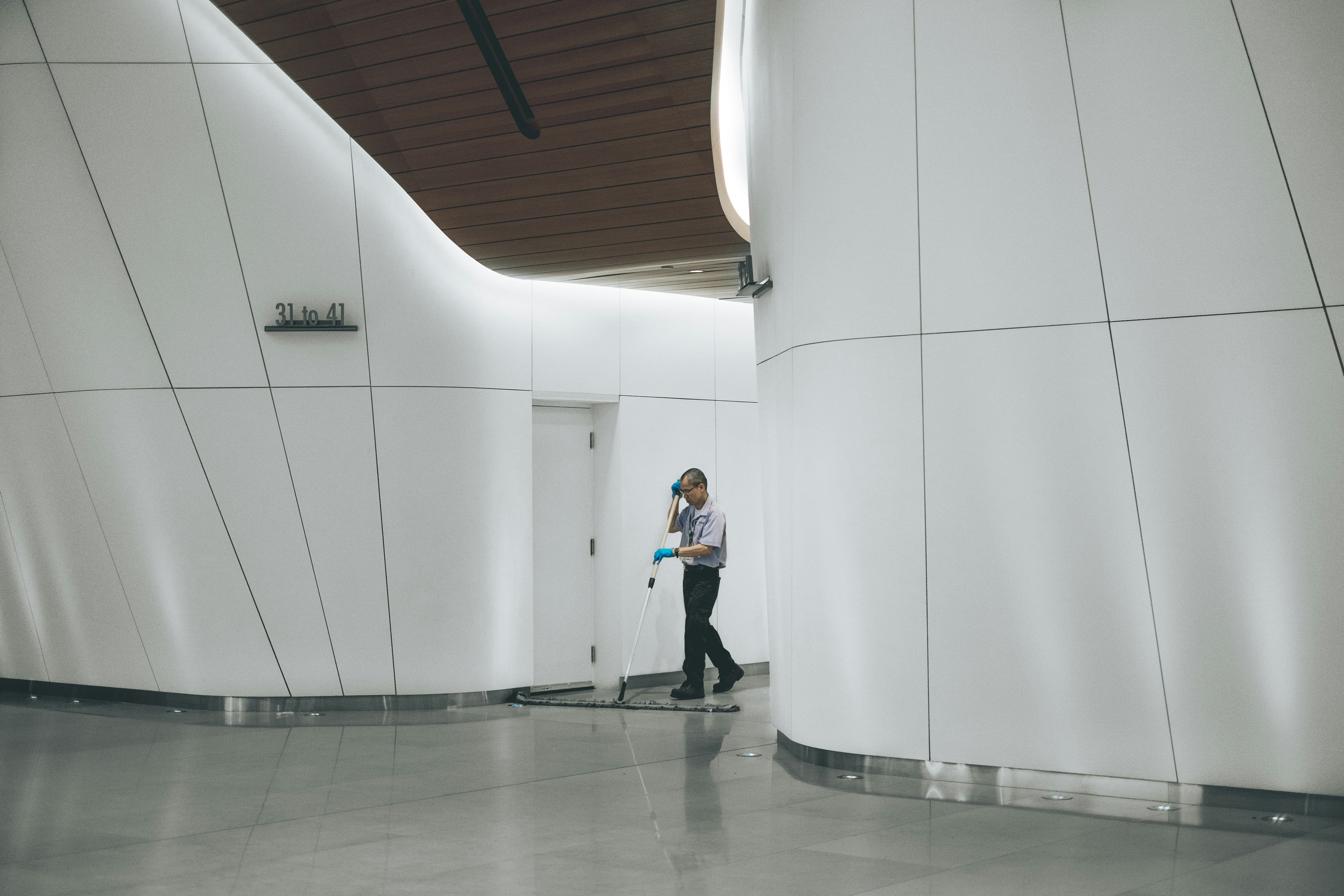Professional janitor mopping a modern commercial building hallway