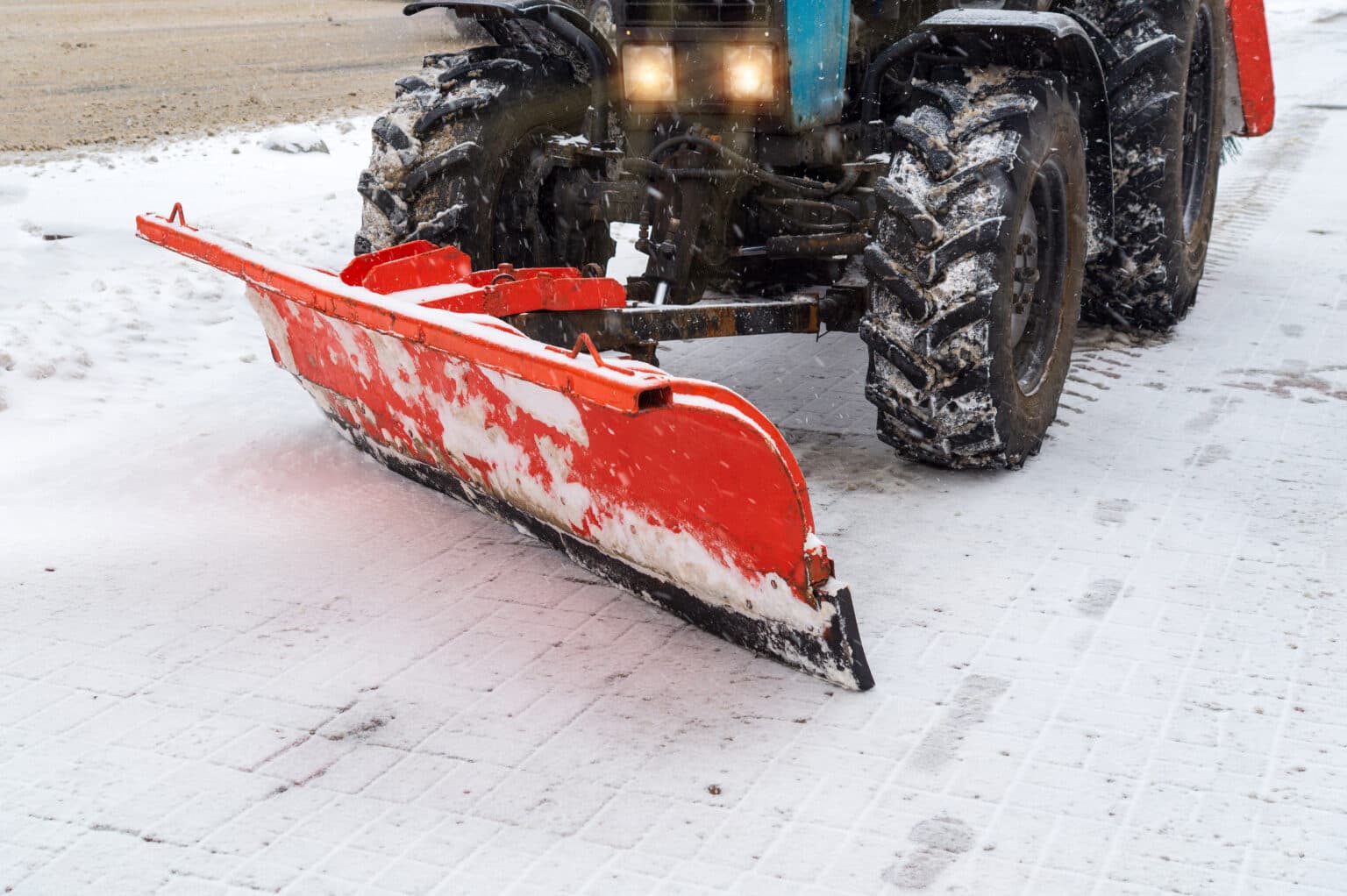Snow plow blade clearing a commercial parking lot during a winter storm