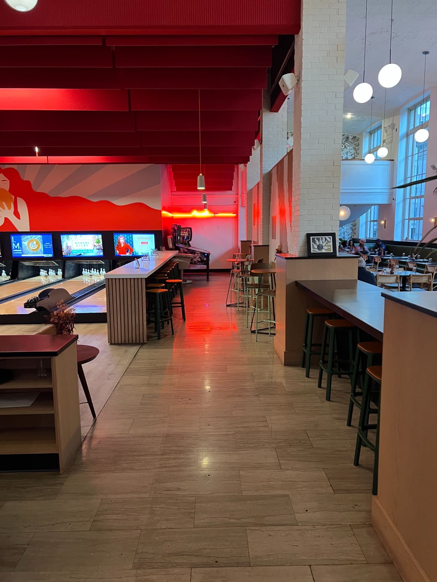 Polished commercial bowling and entertainment venue with bar seating, illuminated lanes, and dramatic interior finishes